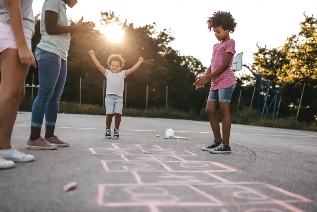 Parent and child using sidewalk chalk during outdoor family activities for child development