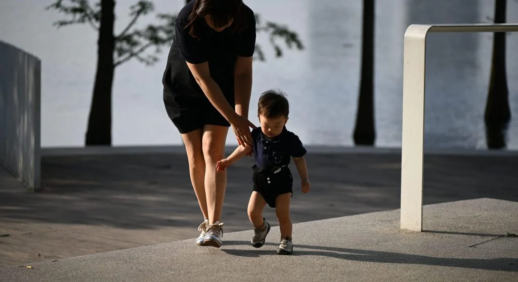 Child trying independently while a parent holds back from stepping in too soon
